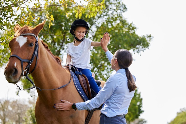 Young girl on a brown horse with her instructor